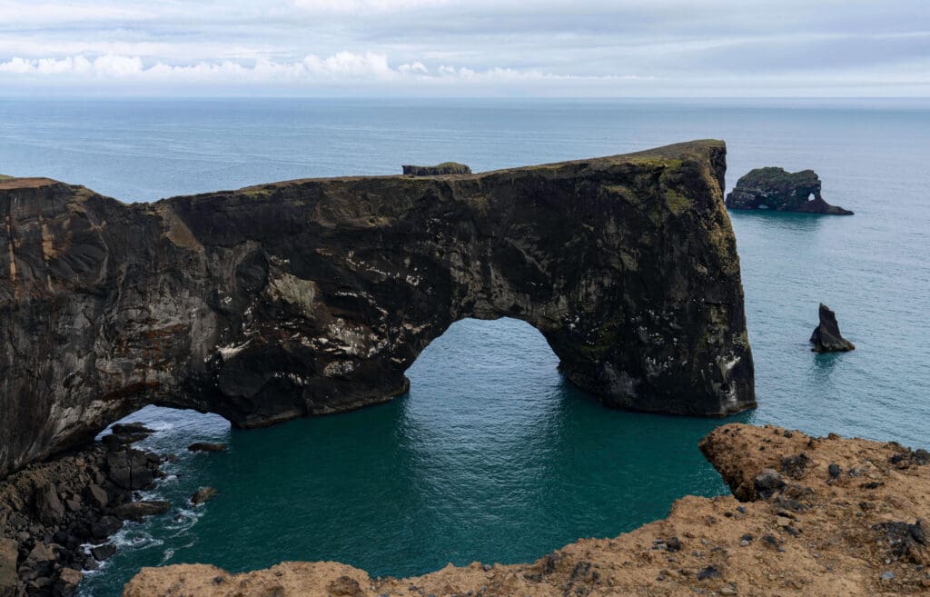 Large arched cliffs extending into the sea which can be seen from the Dyrhólaey Lighthouse