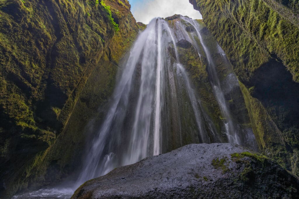 The Gljufrabui waterfall lightly running down the cylindrical cutout's open topped mossy walls