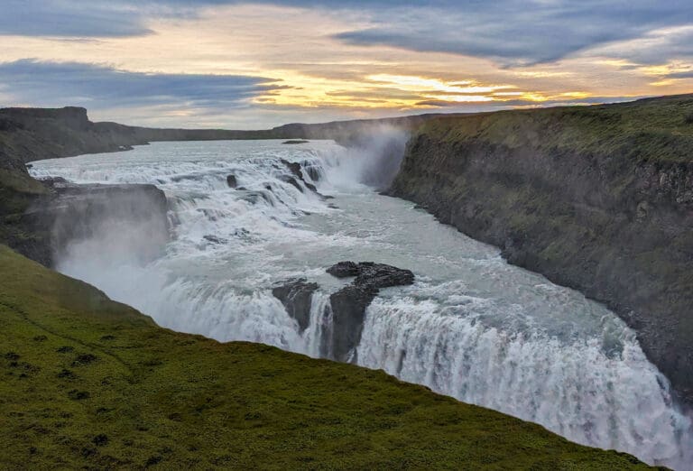 The sun begins to rise over the Iceland landscape bringing light to the expansive Gullfoss waterfall