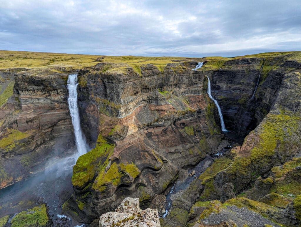 Two Haifoss waterfalls plumet down the cavernous multi-colored rock cliffs dug into the environment