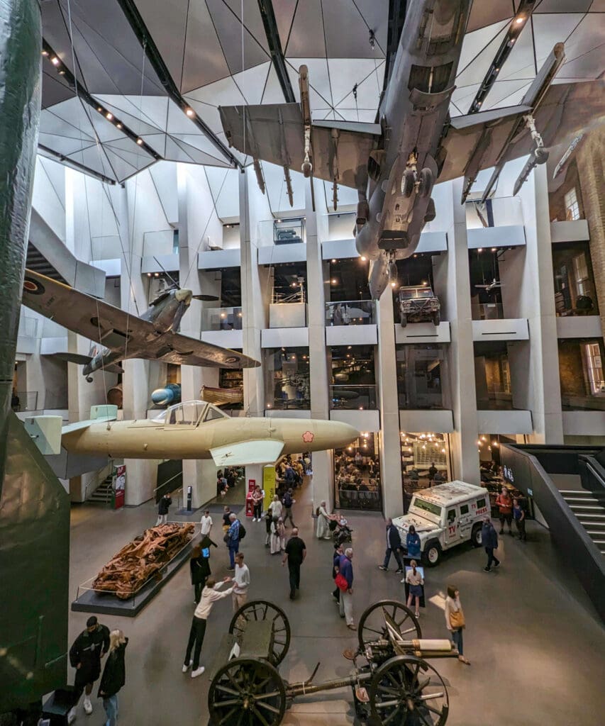 Multiple aircraft and vehicles from different war eras hanging from the ceiling and walls of the Imperial War Museum