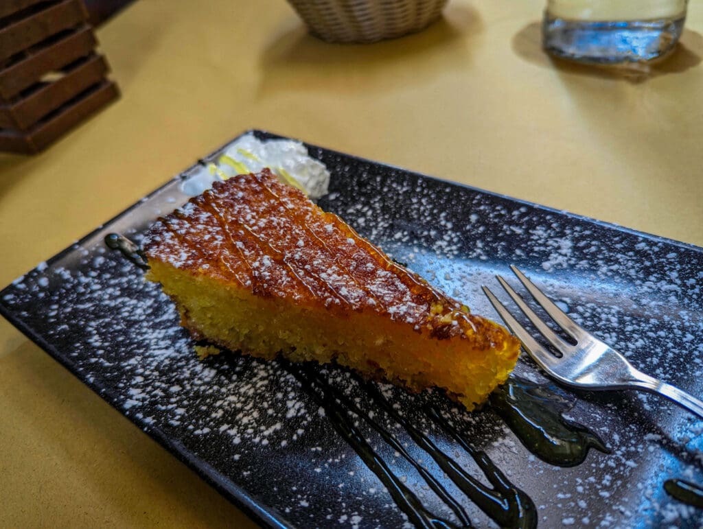 Tart lemon drizzle coats a sweet slice of lemon cake splashed with powdered sugar at La Locanda Gesù Vecchio in Napoli