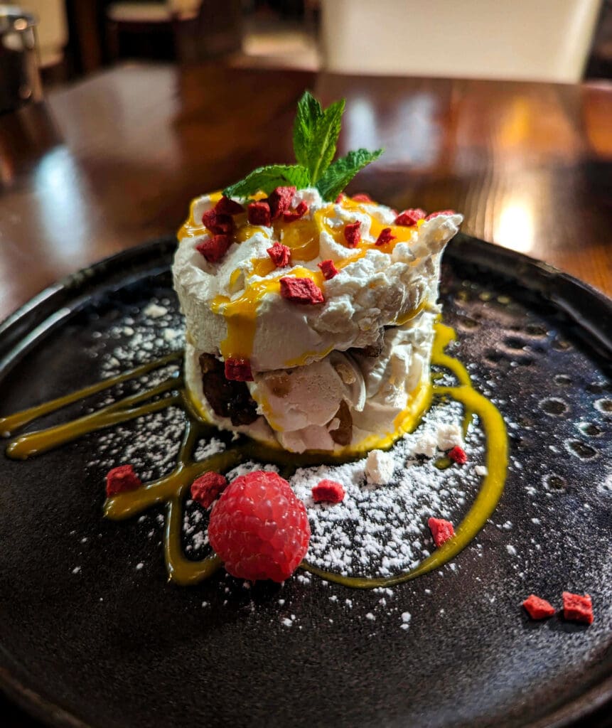 A colorful cylindrical sweet desert treat with tasty yellow drizzle and fresh fruit served at L'Osteria di Santa Marina in Venice