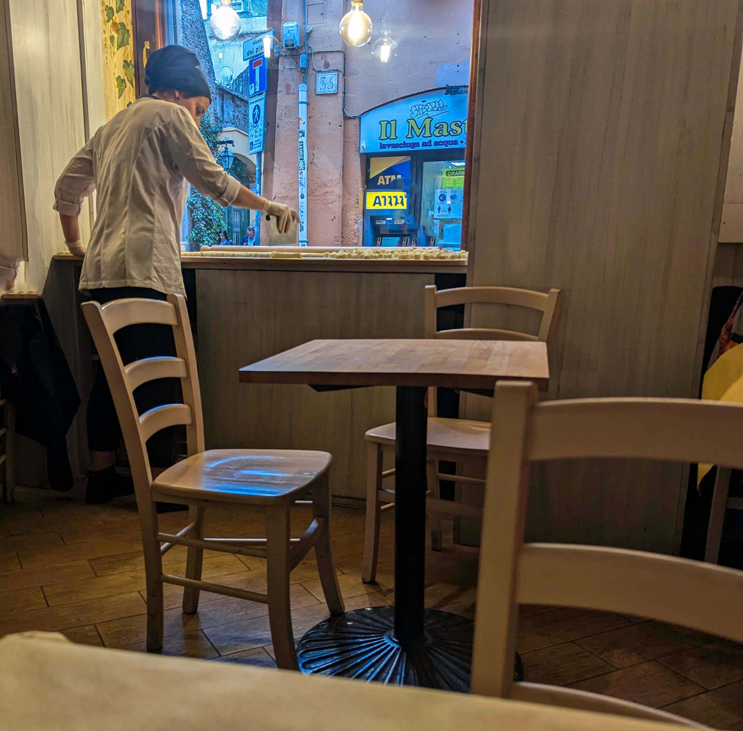 A woman cuts fresh pasta in the window for all to see as they pass the Pasta e Vino Osteria restaurant