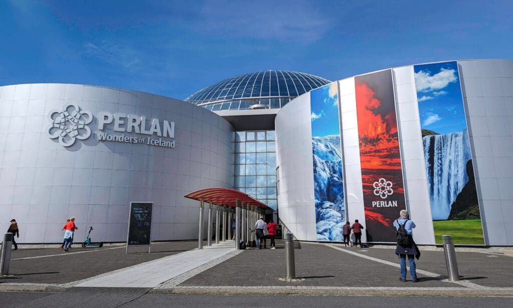 The silvery outside of the Perlan Museum with banners showcasing Icelands environment