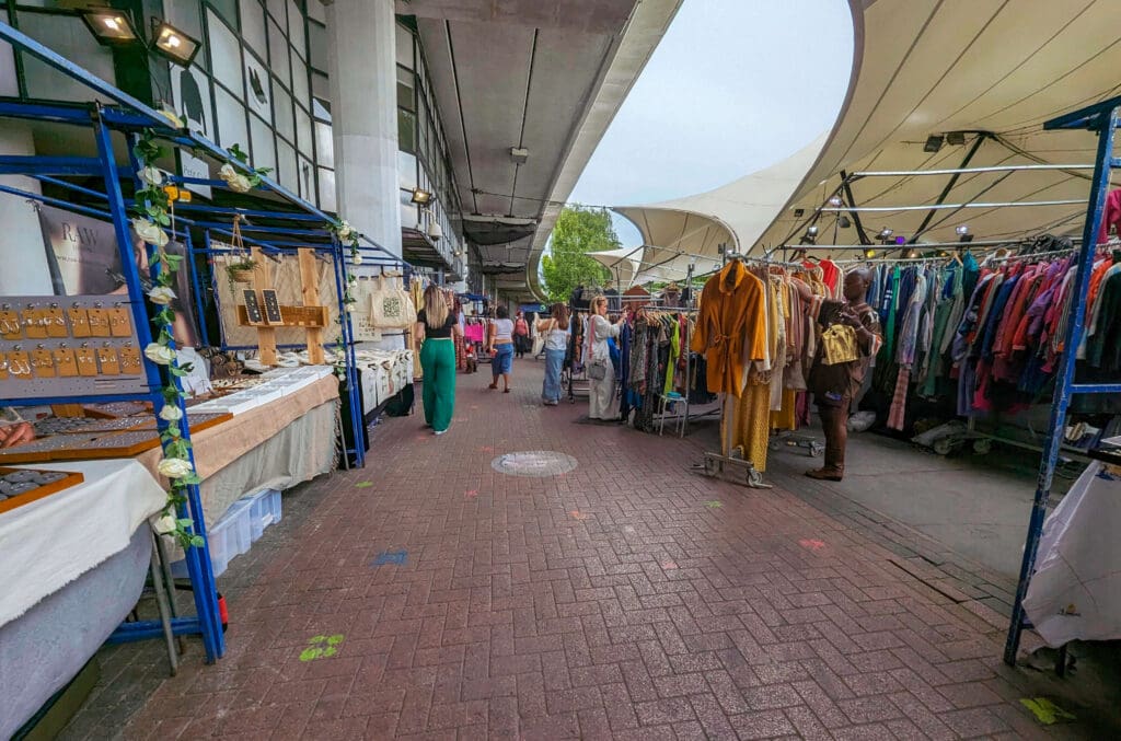 Racks of secondhand clothes and jewelry stands selling handmade items at Portobello Market in London