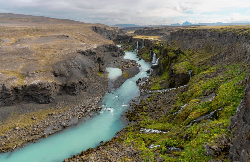 Dreamy light blue water of the Sigöldugljúfur waterfall cutting through the open grassy Icelandic landscape