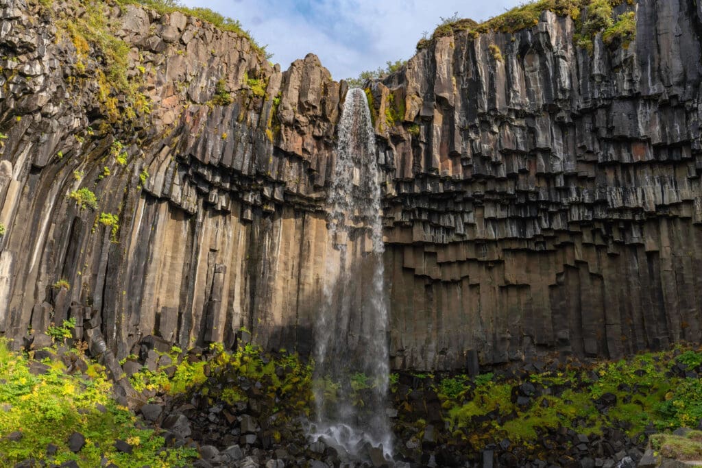 Brown basalt pillard walls creating a funnel for the Svartifoss waterfall