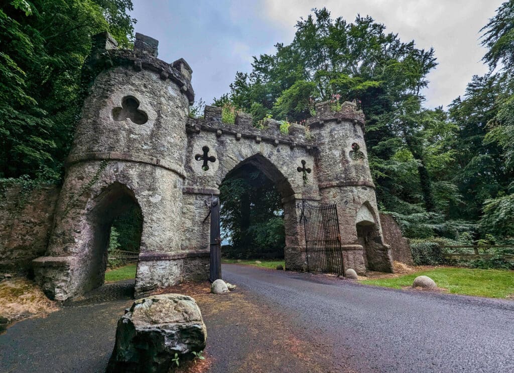 A centuries old, weathered stone castle gate marks the entrance to Tollymore Park