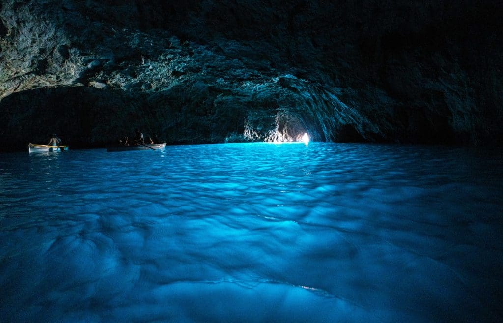 Blue reflections bounce off cave walls as the opening illuminates the blue grotto