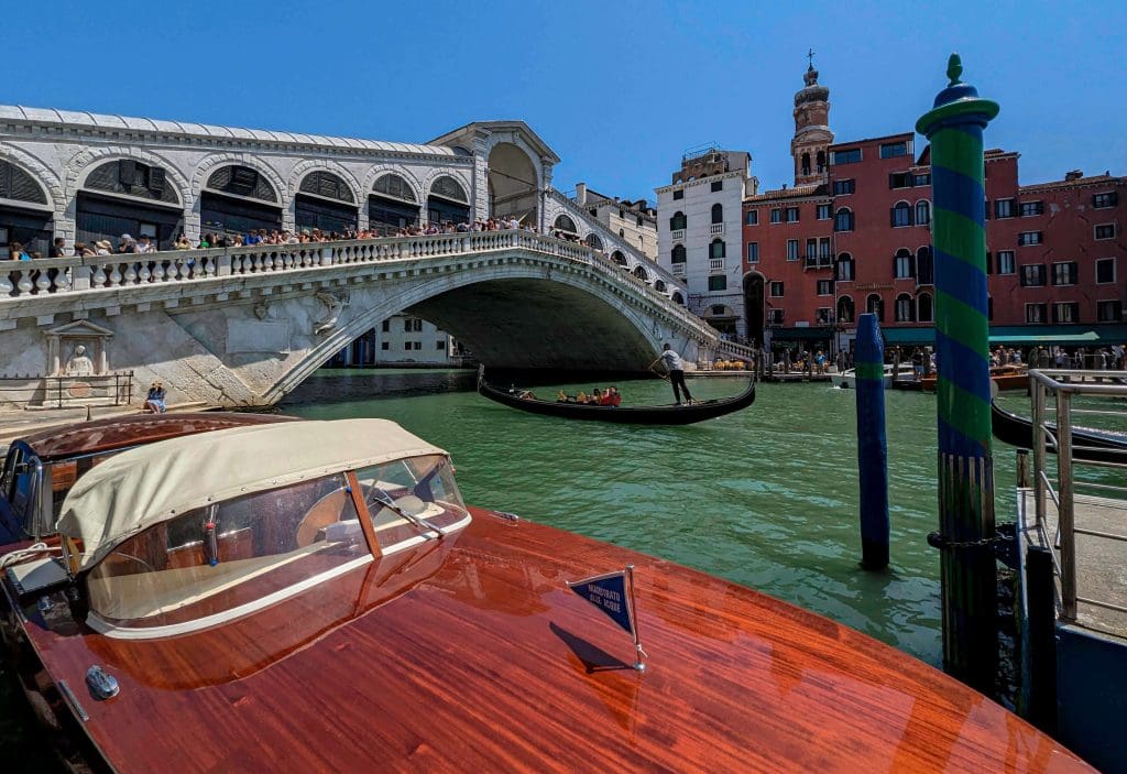 The beautiful white rialto bridge in Venice Italy with a gondola floating underneath, one of the best things to do in Italy