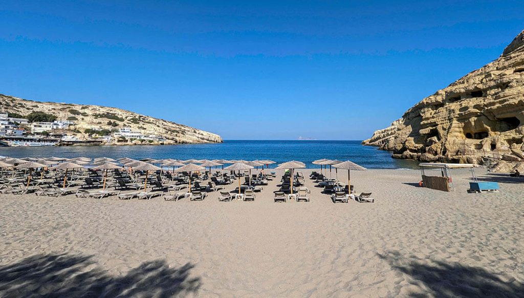 Lounge chairs and ancient cliff caves at Matala Beach make for one of the most unique beaches in Greece.