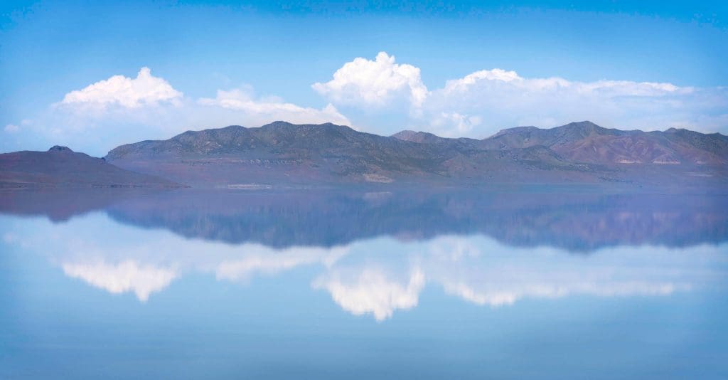 Clouds and distant mountains reflect off of the glass like still water of Antelope Island, the most underrated state park in Utah.