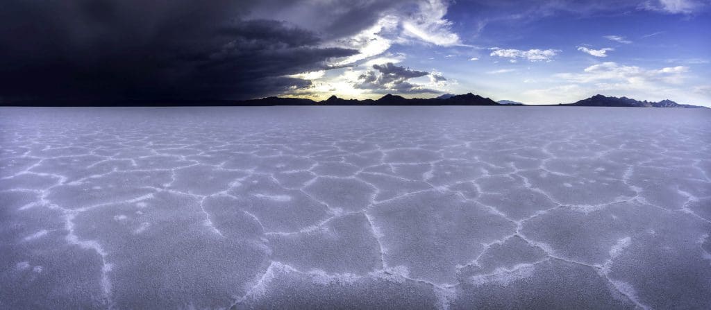 The stunning sight of the sky split in two, one half stormy the other sunny while the sun sets between them over the Bonneville Salt Flats