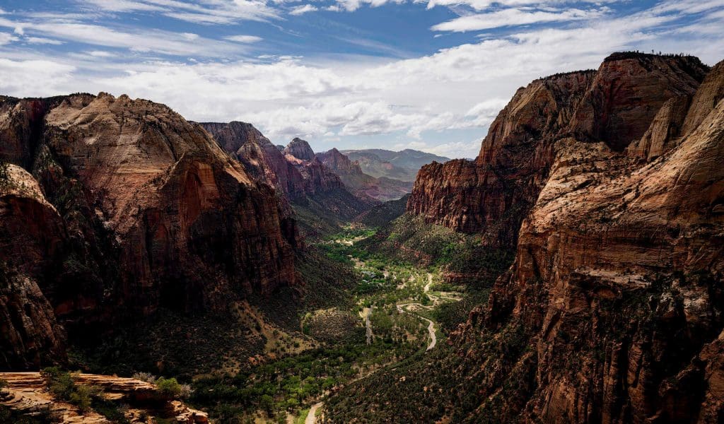 Looking down the Zion National Park valley with towering mountains extending into the horizon from atop Angels Landing.