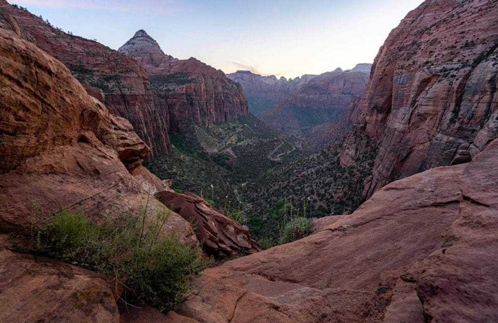 The sun sets while looking off the edge of the Canyon Overlook, one of the most underrated hikes in Zion National Park.