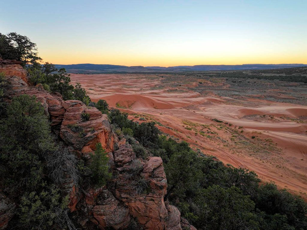 Red rocks cascading down the forest hills while the Coral Pink Sand Dunes sit in the sunset shadows as one of the best spots for Utah outdoor adventurers.