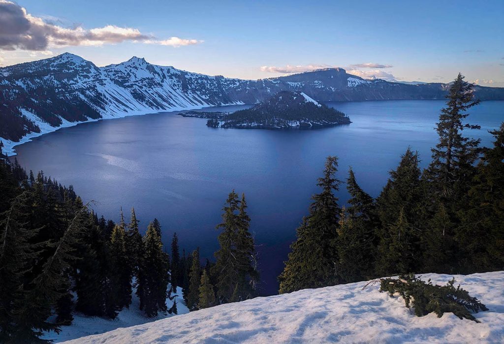 Looking over the snowy Oregon landscape of a massive crater filled with water and surrounded by mountains.