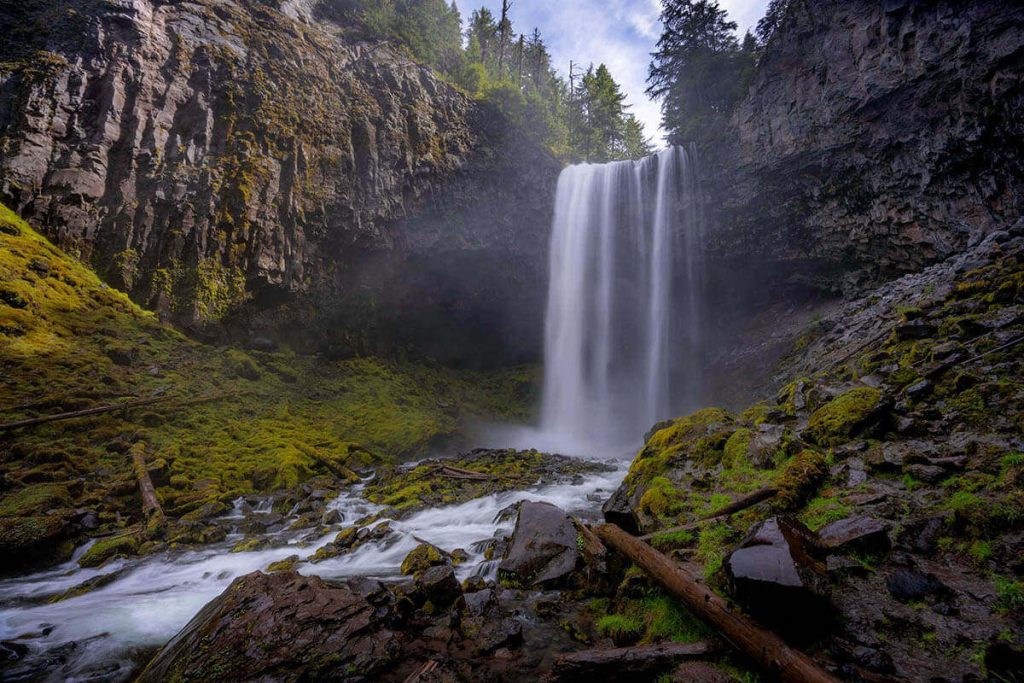 Water lightly flows off an open cliff down to the mossy rocks below in a top Oregon photography spot.