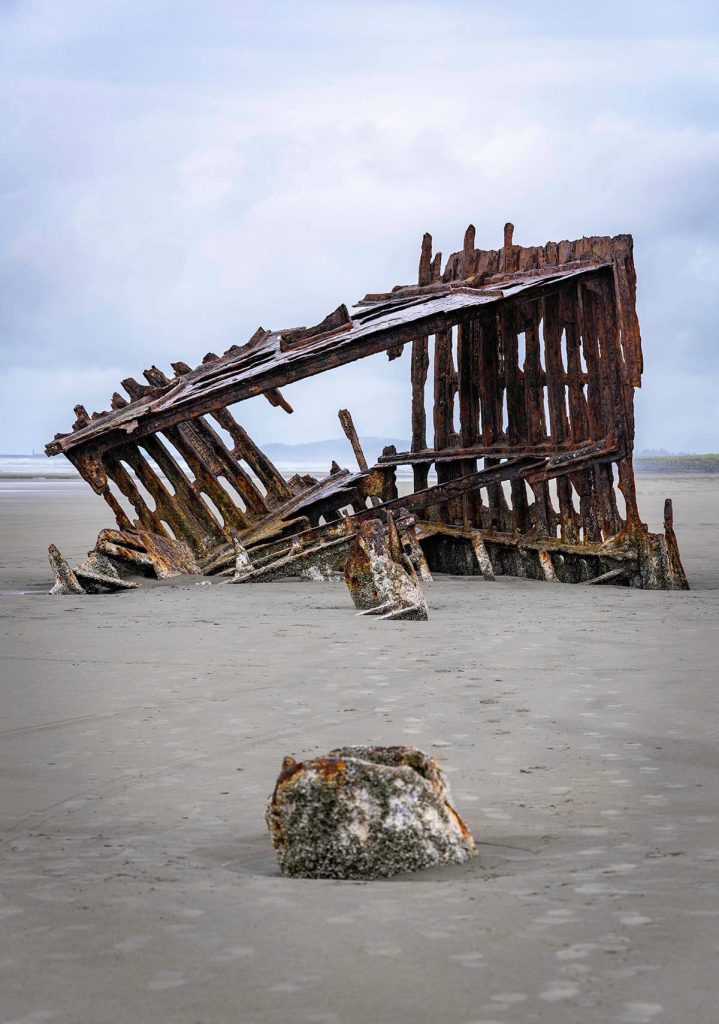 An eerie sight of the worn remains of the century old ship sticking out of the sand at a top Oregon photography spot.