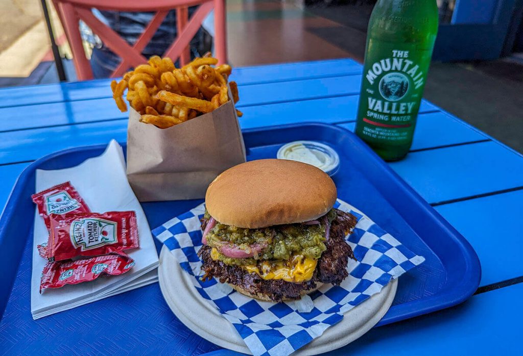 An incredible burger from Goldburger with layers of cheese, patties, spices, and a side of crispy curly fries.