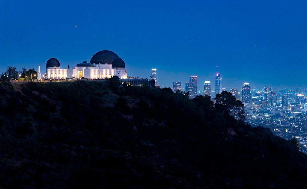 Seeing Griffith Observatory lit up as it sits on the cliffside overlooking the night sky and illuminated city below.