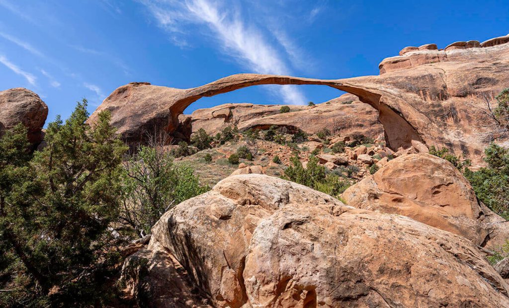 Looking up at the extremely long and narrow Landscape Arch as it stretches from one cliff to another.