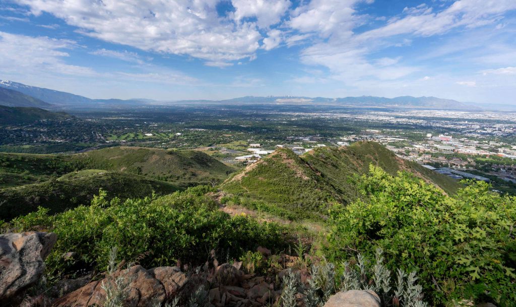 A hiking trail in Utah that leads up small mountains to overlook the lush environment and Salt Lake City beyond.