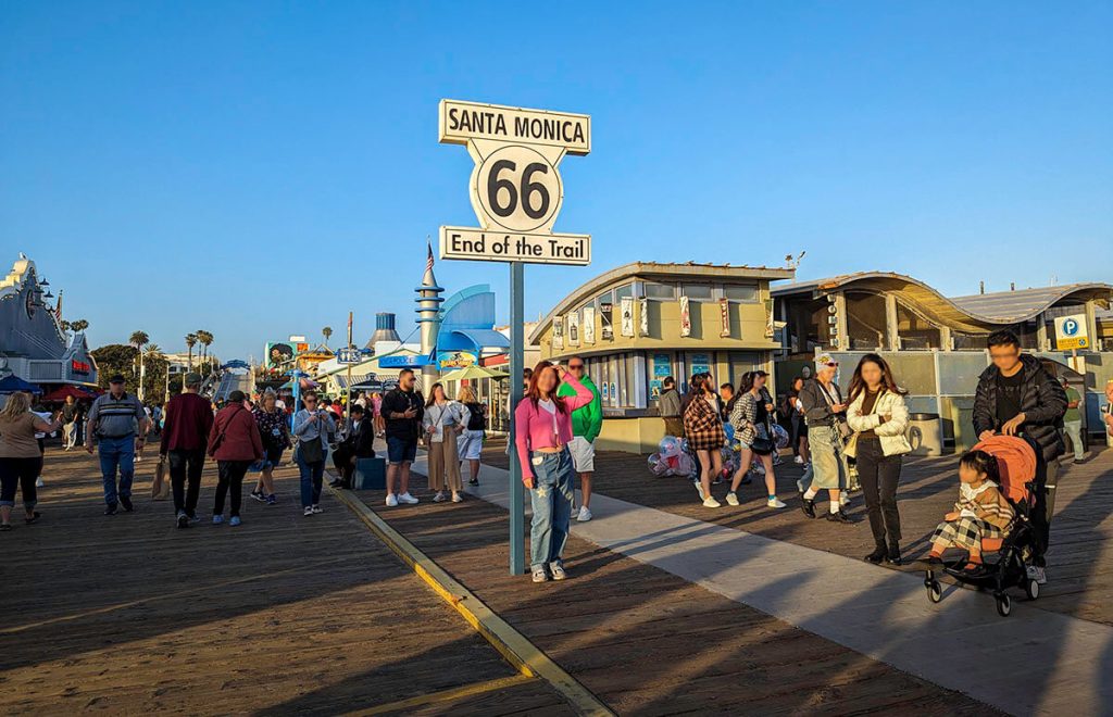 A sign shows the final endpoint for Route 66 sitting on the energetic Santa Monica Pier, a once in a lifetime thing to do in Los Angeles.