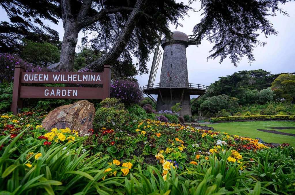 Vibrant flowers make up the foreground of the Queen Wilhelmina Garden as a stone windmill sits in the background.
