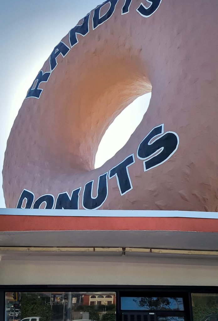 Looking up at the giant donut decoration standing atop the roof of Randy's Donuts.