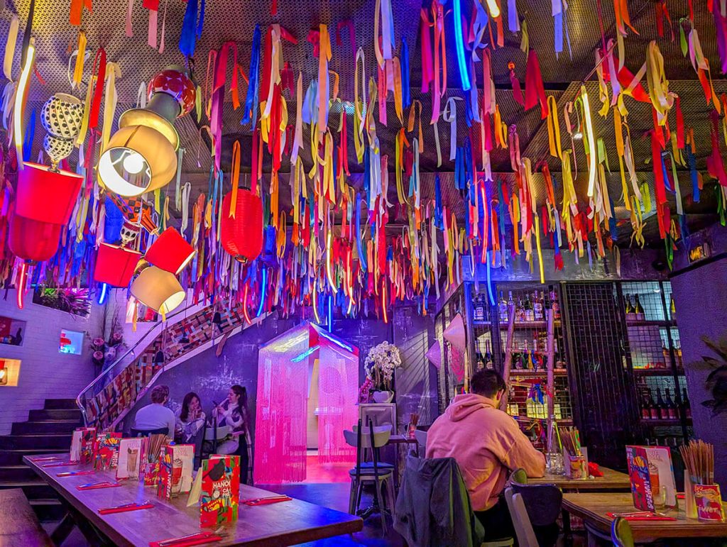 Bright colored streamers hang down from the ceiling in the fun restaurant of Hanoi Ca Phe Opera in Paris.