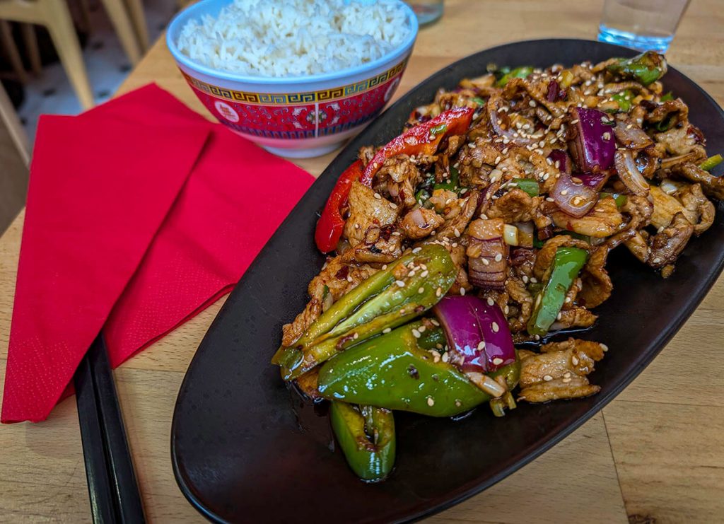 The savory Pork stir fry with a bowl of rice sits atop the table at O31 Au Piment Sichuan.