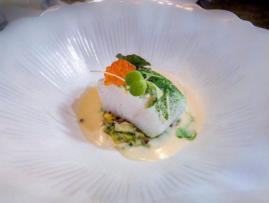 Fine and perfectly prepared fish sits on a plate at the incredible place to eat in Paris, Restaurant H.