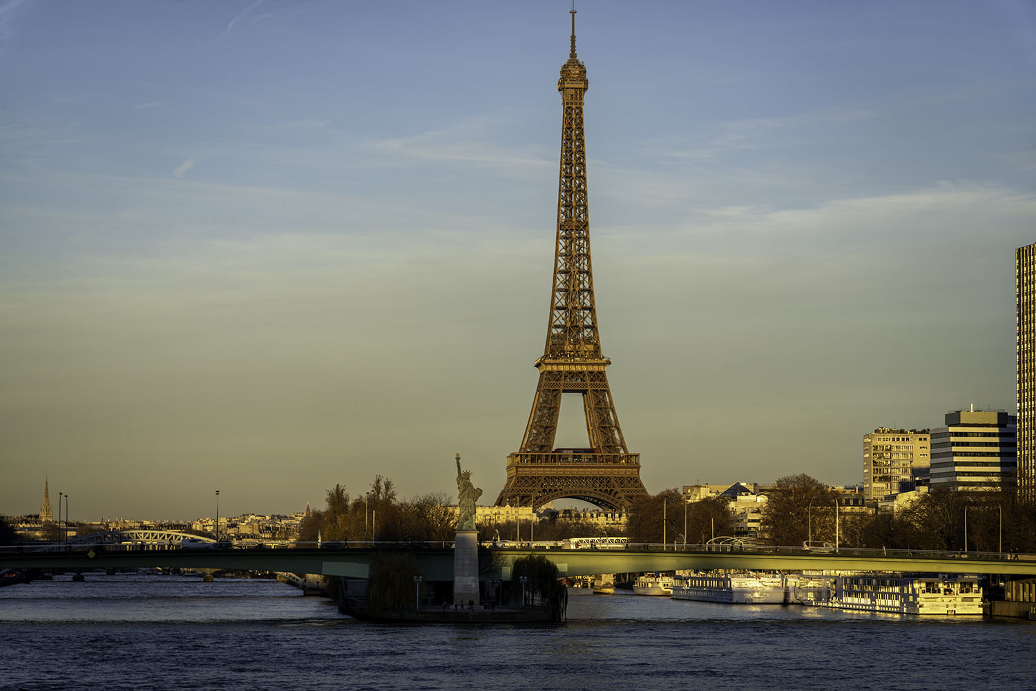 A warm sunset dances off the statue and waterwhile the tower rises in the background at this stunning Eiffel Tower view.